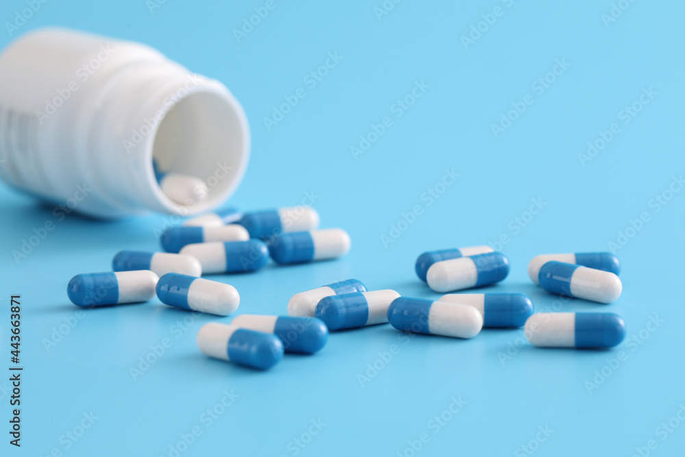 pills capsules with bottle isolated on blue background