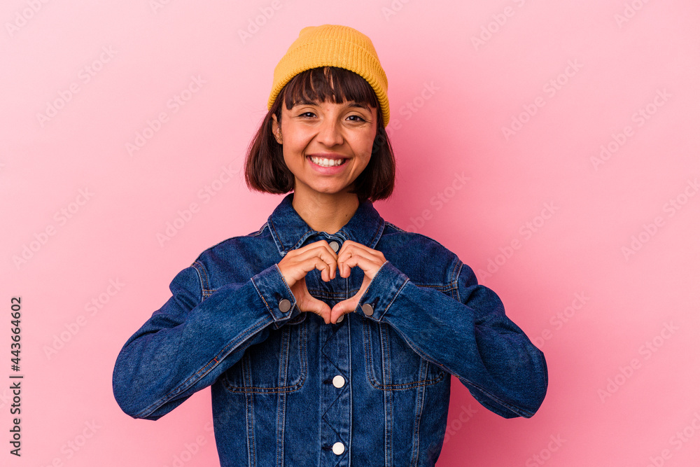 Young mixed race woman isolated on pink background smiling and showing a heart shape with hands. Young mixed race woman isolated on pink background smiling and showing a heart shape with hands.