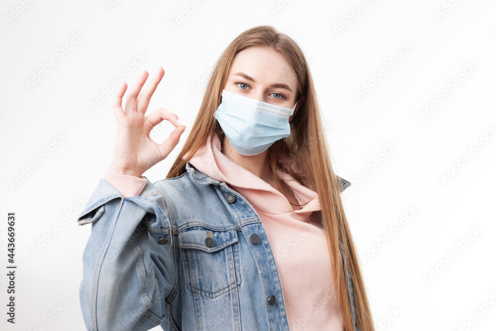 Young woman in medical mask showing okay gesture isolated on white background Young woman in medical mask showing okay gesture isolated on white background
