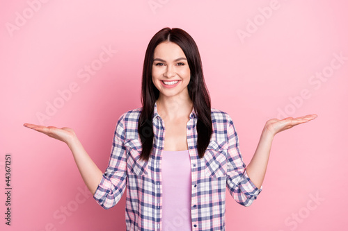 Photo portrait of girl scaling comparing empty spaces isolated on pastel pink color background