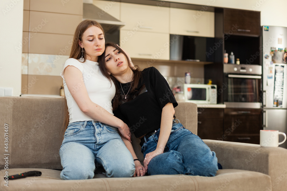 Girl comforting her best friend while sitting on the couch Girl comforting her best friend while sitting on the couch