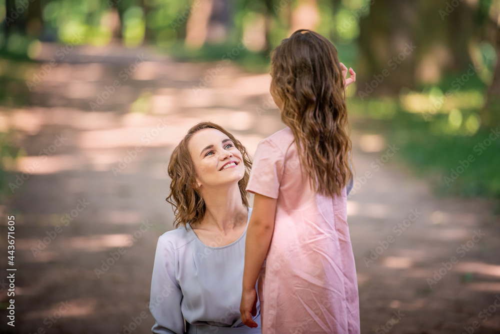 Mother and daughter are hugging in park. Happy family concept. Beauty nature scene with family outdoor lifestyle. Happy family resting together. Happiness and harmony in family life. Mother and daughter are hugging in park. Happy family concept. Beauty nature scene with family outdoor lifestyle. Happy family resting together. Happiness and harmony in family life.