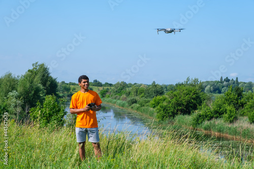 African American man operating drone with controller in hands on the meadow