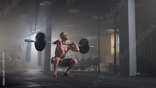 Slow motion of crossfit athlete performs clean and jerk. Young man doing the clean and jerk weightlifting exercise at the gym.