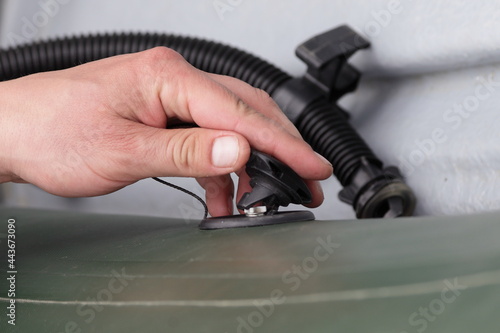 Obraz na płótnie A man's hand opens the valve cover for blowing off an inflatable boat against the background of a pump hose w salonie