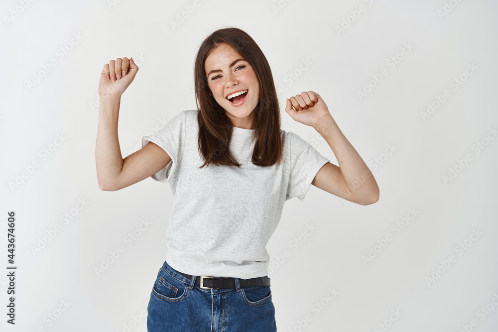 Happy young woman dancing and having fun, smiling and expressing positive emotions, standing over white background