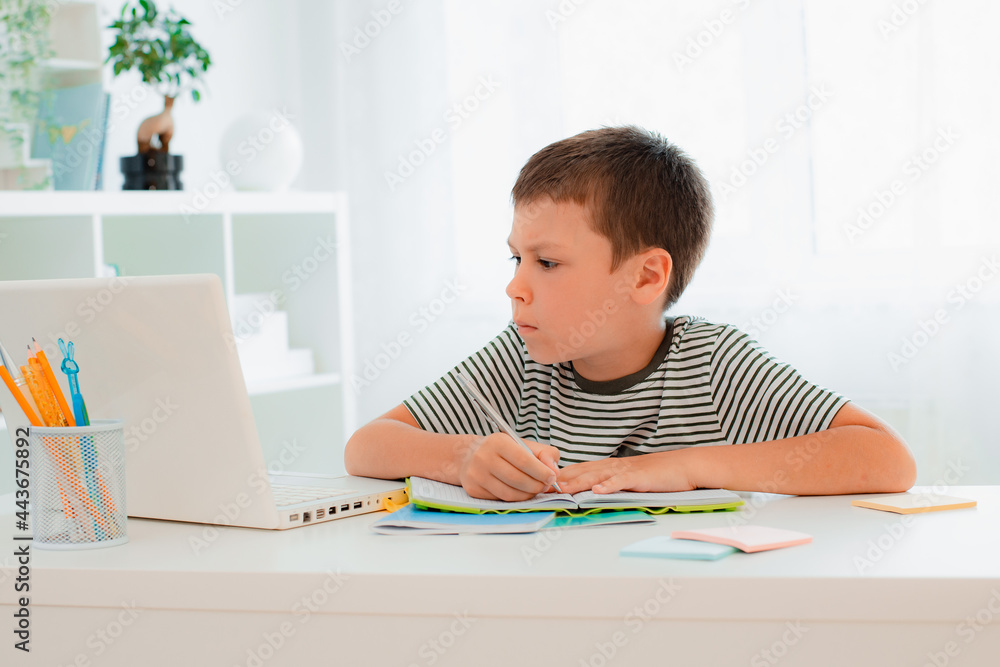 Distance learning online education. A schoolboy boy studies at home and does school homework. A home distance learning. Distance learning online education. A schoolboy boy studies at home and does school homework. A home distance learning.