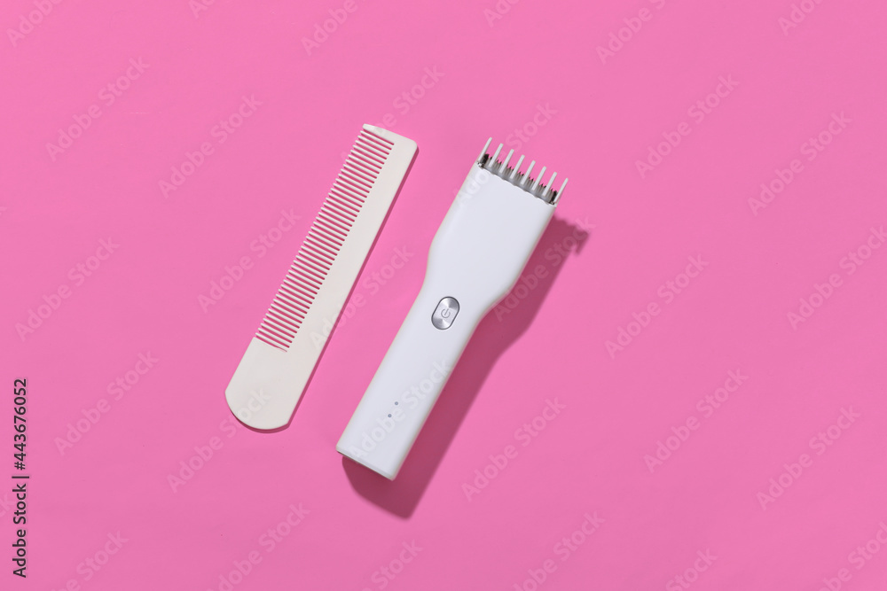 Wireless hair clipper and comb on pink bright background. Top view Wireless hair clipper and comb on pink bright background. Top view