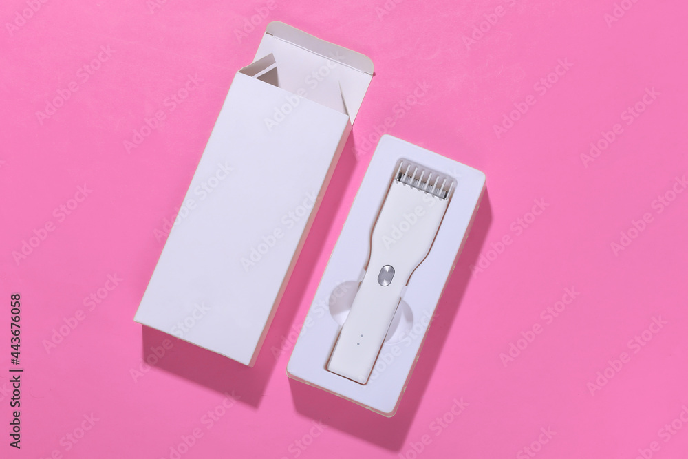 Fototapeta premium New Wireless Hair Clipper in box on pink bright background. Top view
