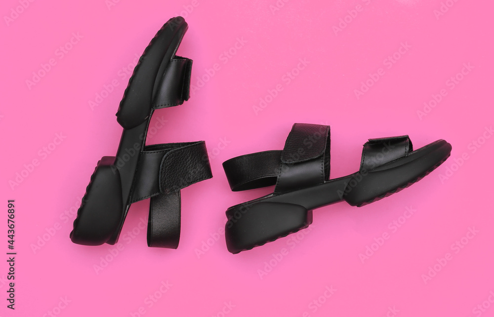 Leather black women's sandals on pink background. Top view. Flat lay Leather black women's sandals on pink background. Top view. Flat lay