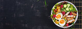 Grilled chicken meat and fresh vegetable salad of tomato, cucumber, egg, lettuce and raspberry. Ketogenic diet. Buddha bowl dish on dark background. Top view, banner