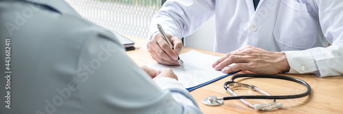 Fotografie Male doctor with stethoscope is writing symptom of patient medication history an