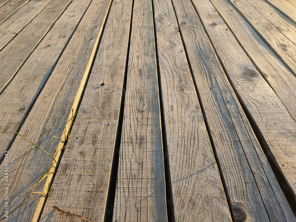 Wooden floor with grass between long thin lines at sunset Wooden floor with grass between long thin lines at sunset