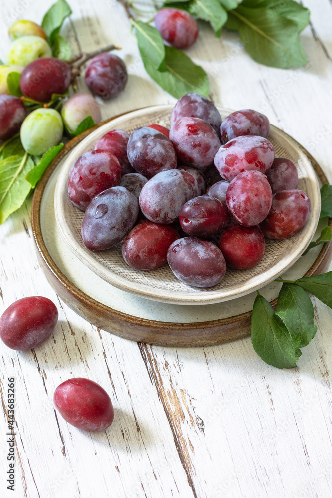 Seasonal food background. Ripe juicy plums in a bowl on a rustic wooden table. Copy space. Seasonal food background. Ripe juicy plums in a bowl on a rustic wooden table. Copy space.