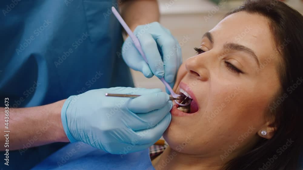 Closeup to the camera beautiful female have a oral care examination in a modern luminous dental clinic Closeup to the camera beautiful female have a oral care examination in a modern luminous dental clinic