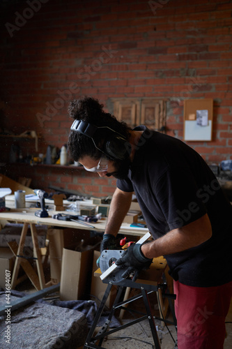 man polishing wood in workshop with electric saw © Ekaitz