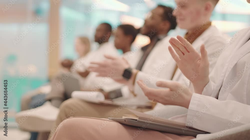 Side-view close-up of unrecognizable hands of medical students in white coats applauding to professor thanking for interesting lecture Side-view close-up of unrecognizable hands of medical students in white coats applauding to professor thanking for interesting lecture