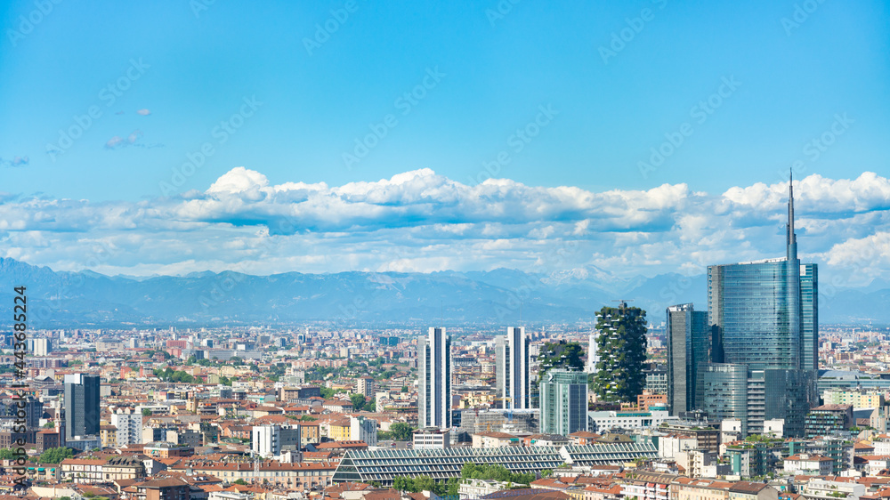 Obraz premium Aerial view of Milan skyline, Italy, with business skyscrapers. In the distance the alps mountain range is visible. Blue sky and white clouds on the background.