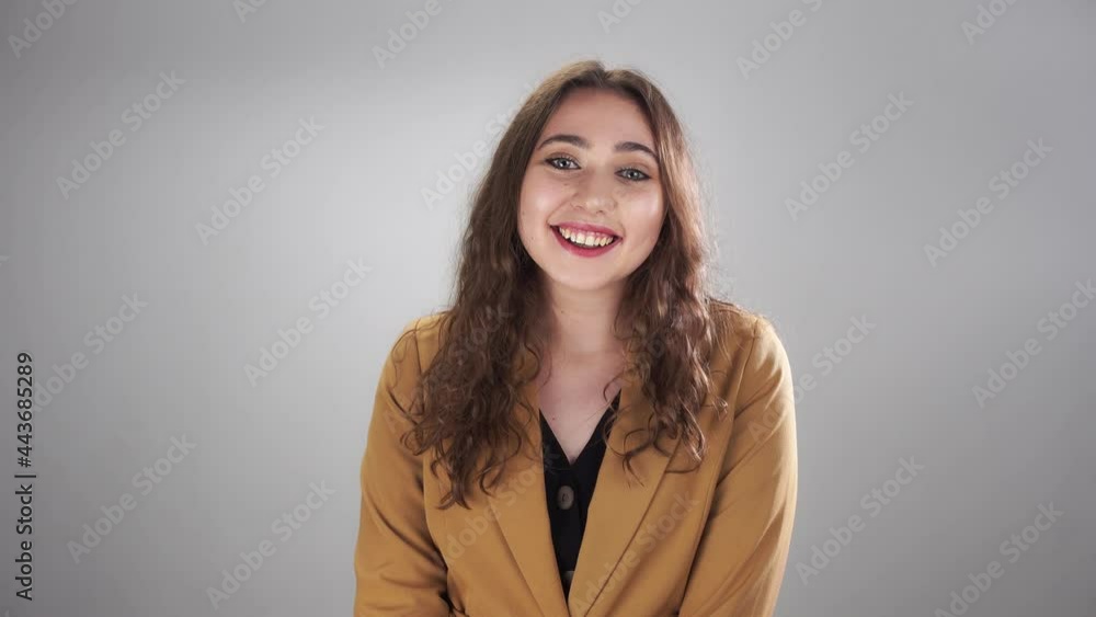 Portrait of a young woman saying hello and waving hand then listening to somebody on the white background. A smiling caucasian lady is participating in a dialogue. Concept of meeting and communication Portrait of a young woman saying hello and waving hand then listening to somebody on the white background. A smiling caucasian lady is participating in a dialogue. Concept of meeting and communication