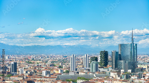 Aerial view of Milan skyline  Italy  with business skyscrapers. In the distance the alps mountain range is visible. Blue sky and white clouds on the background.