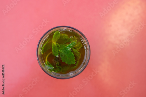 Top view of a Glass of moroccan tea with mint plant with copy space in red background