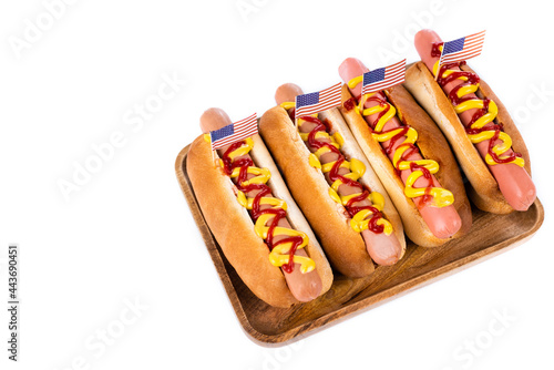 delicious hot dogs with small usa flags on wooden tray isolated on white