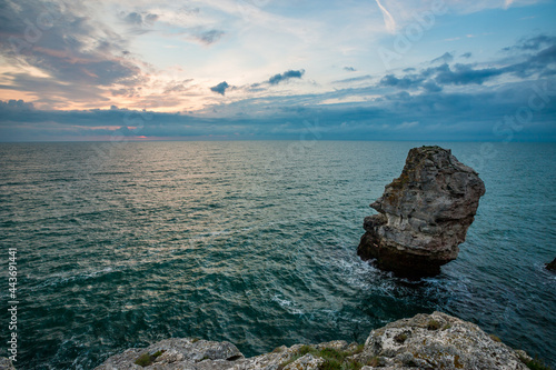 Sunrise at Black Sea, Bulgaria, near Tyulenovo village. Sea rock in the foreground, called "The Needle", cloudy colorful sky