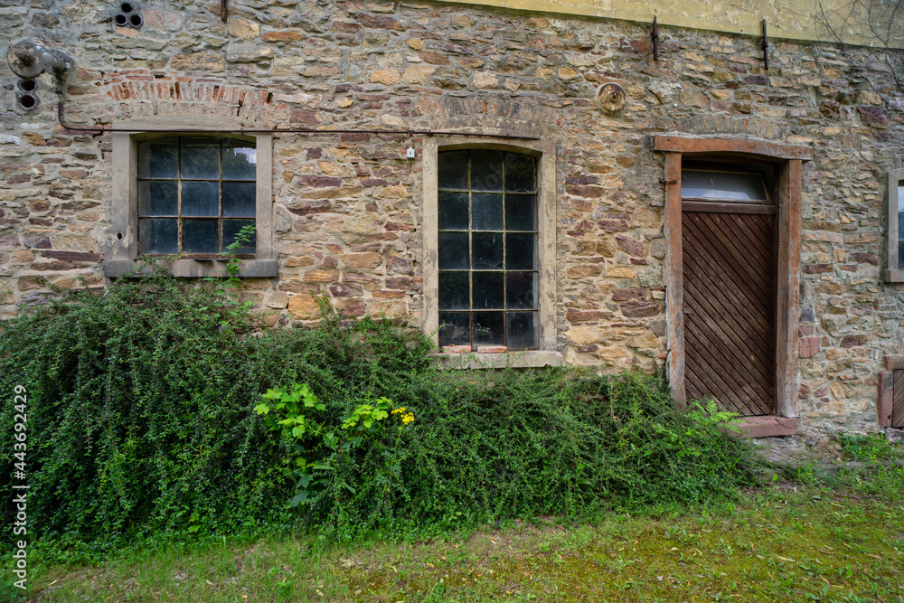 Lost place, old stone building with wooden door and transom window.