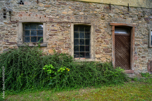 Lost place, old stone building with wooden door and transom window.