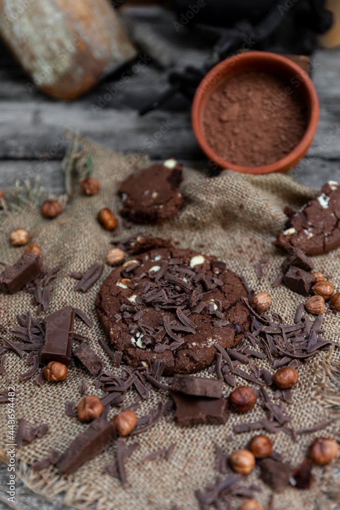 Chocolate cookies with hazelnuts , cocoa and pieces of dark chocolate on the rustic kitchen table Chocolate cookies with hazelnuts , cocoa and pieces of dark chocolate on the rustic kitchen table