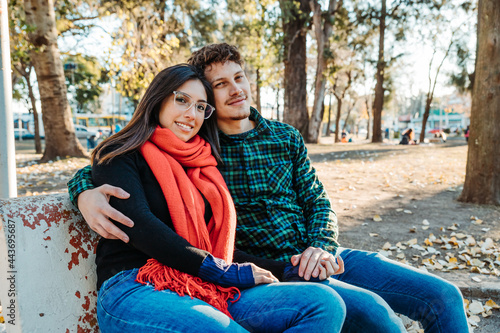 young couple sitting in park enjoying afternoon