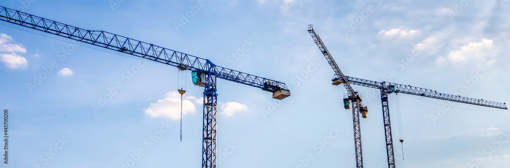 Banner of construction tower cranes with cabins in a blue sky. Industry concept