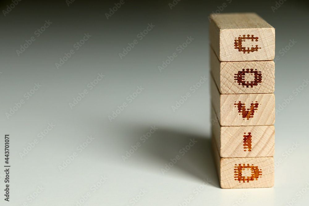 COVID is a word written on a wooden block. COVID is the word for your design, concept.