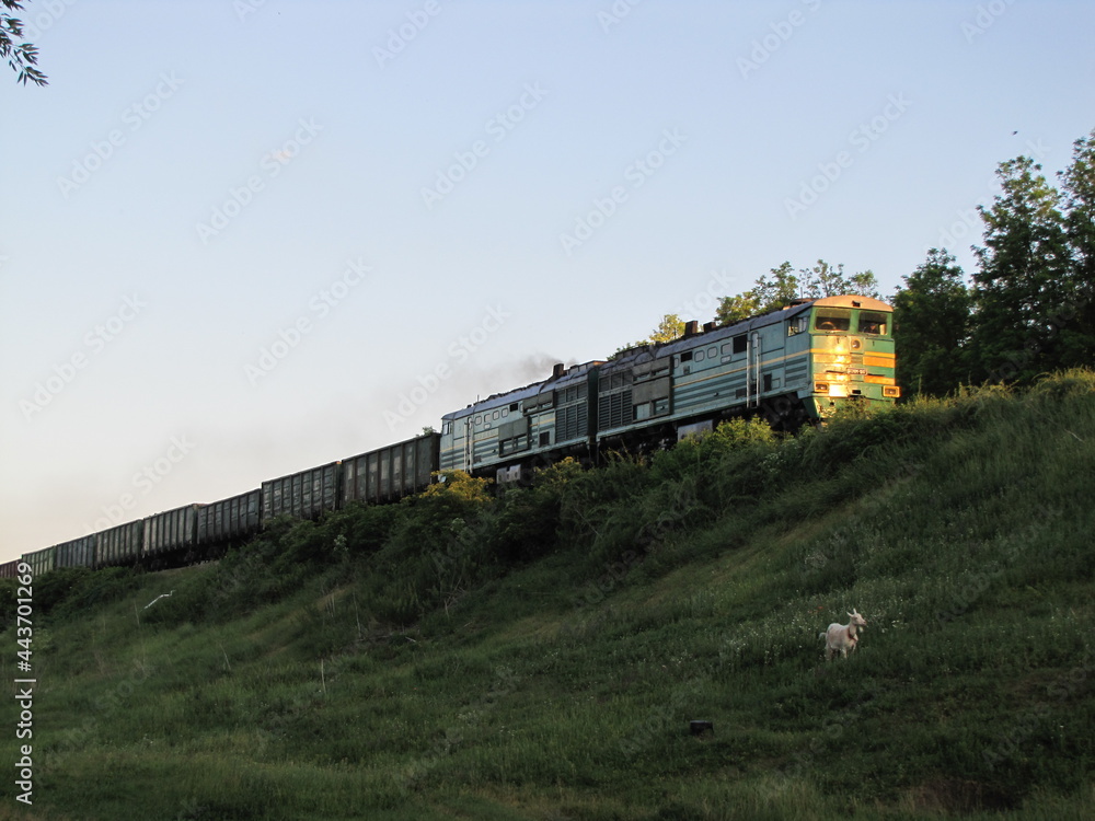 An old Soviet train. A long train train. Railway in the village. A train leaving for the sunset