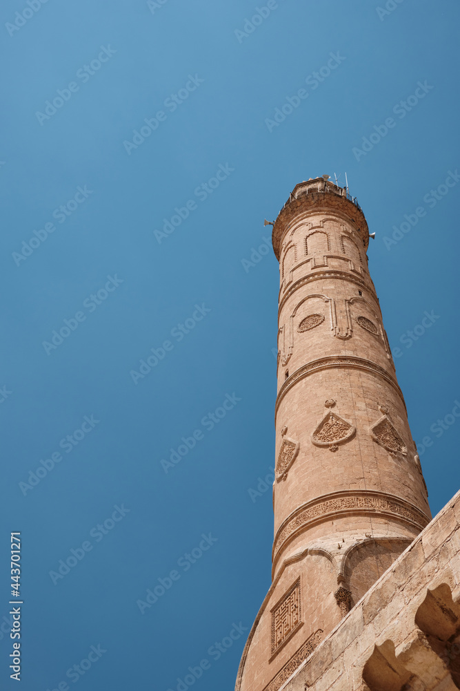 Ancient minaret against bright blue sky. Ulu Cami or Grand Mosque, Mardin, Turkey