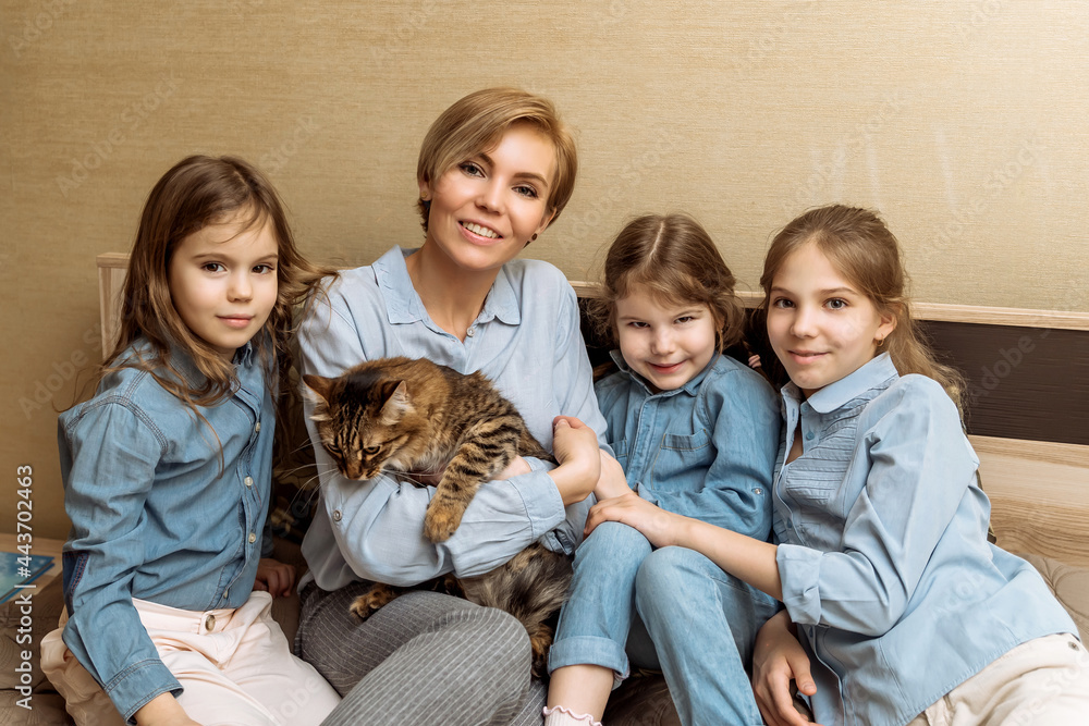 family portrait of a mother and three daughters with a pet with a cat. children play with a domestic cat