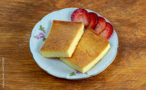Two pieces of fiadone - Corsican cheesecake, on a saucer with strawberry slices. photo
