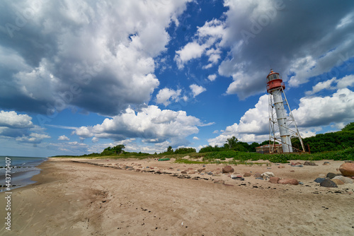 Lighthouse Under a Deep Blue Sky. Sandy beach and sea photo