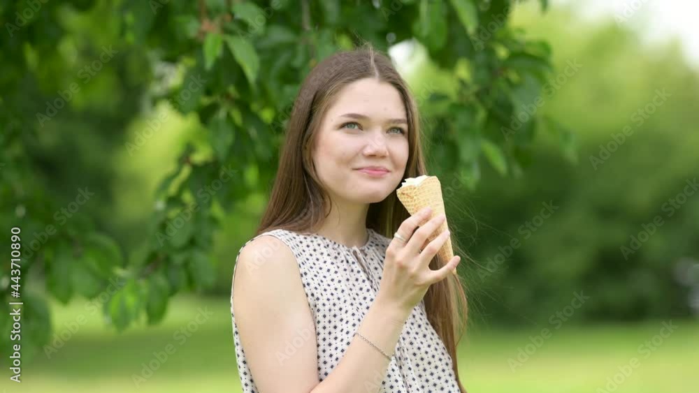 Young smiling girl eating tasty ice cream in the park. Woman with delicious ice cream on summer day. summer lifestyle.