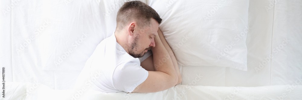 Young man is sleeping peacefully on large white bed Young man is sleeping peacefully on large white bed