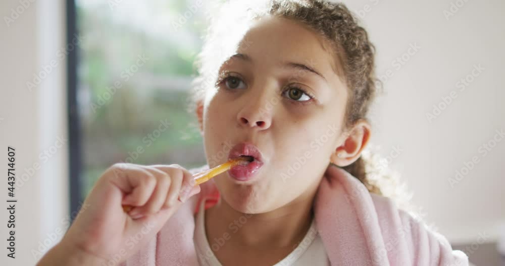 Happy mixed race girl brushing teeth in bathroom Happy mixed race girl brushing teeth in bathroom