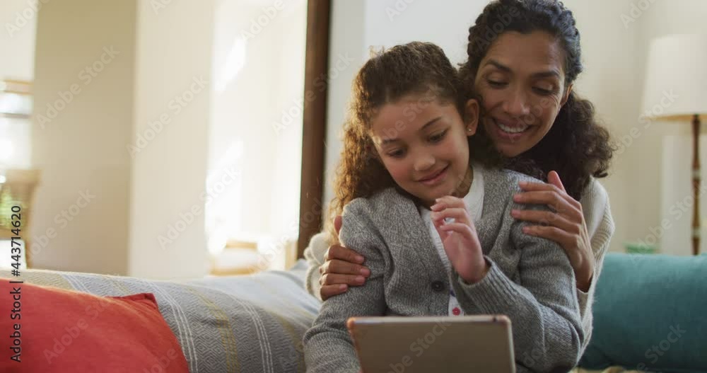 Happy mixed race mother and daughter sitting on the sofa,having fun and using tablet Happy mixed race mother and daughter sitting on the sofa,having fun and using tablet