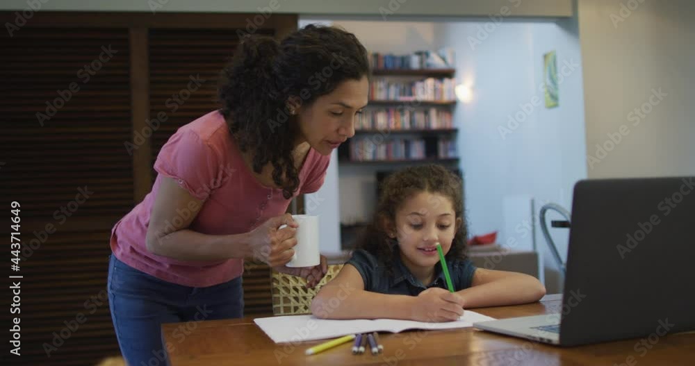 Happy mixed race mother and daughter doing homework together at home Happy mixed race mother and daughter doing homework together at home
