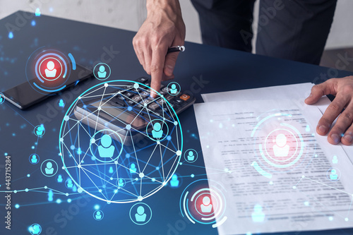 Fototapeta Naklejka Na Ścianę i Meble -  HR specialist researching and analyzing the data of salary on employment market to forecast ongoing expenses of the company using calculator. Hiring new talented officers. Social media hologram icons