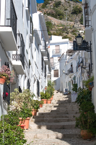 Frigiliana  Spain. Historic  pretty old hill village.  A narrow steep alley in the ancient Moorish quarter. Whitewashed buildings with colorful flowers. Vertical shot with copy space.