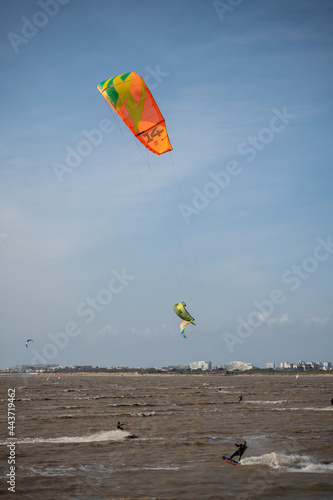 Unknown kitesurfers surf with orange sail on brown water from the Atlantic Ocean in La Rochelle, France. photo