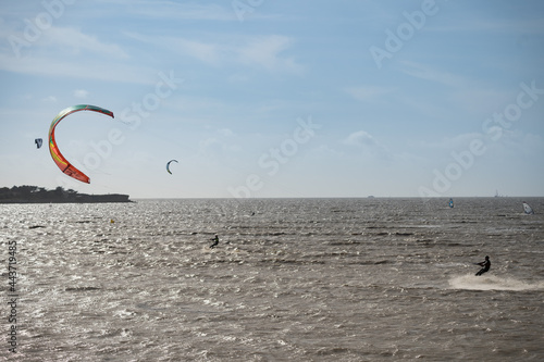 Unknown kitesurfers surf on brown water with waves from the Atlantic Ocean in La Rochelle, France.