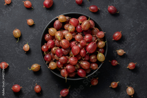 Red gooseberries in a black bowl on a black background, top view. photo
