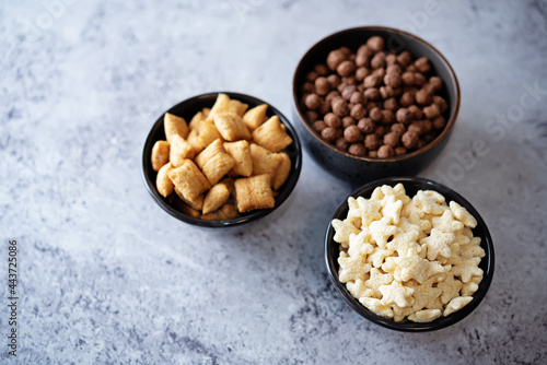 Dried wheat stars, pads and chocolate balls for breakfast in bowls