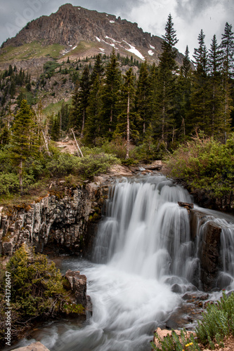 View of a waterfall surrounded by greenery, mountains, and trees in Yankee Boy Basin near Ouray, Colorado. 